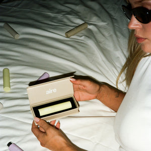 Person holding a mouth spray on a bed with various mouth spray products around aesthetically.